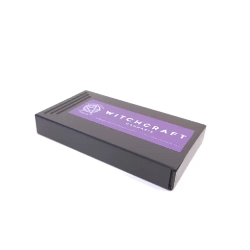 Una scatola nera con un'etichetta viola sulla Witchcraft Cannabis - Confezioni Pre-Roll disponibili presso un dispensario di prim'ordine.